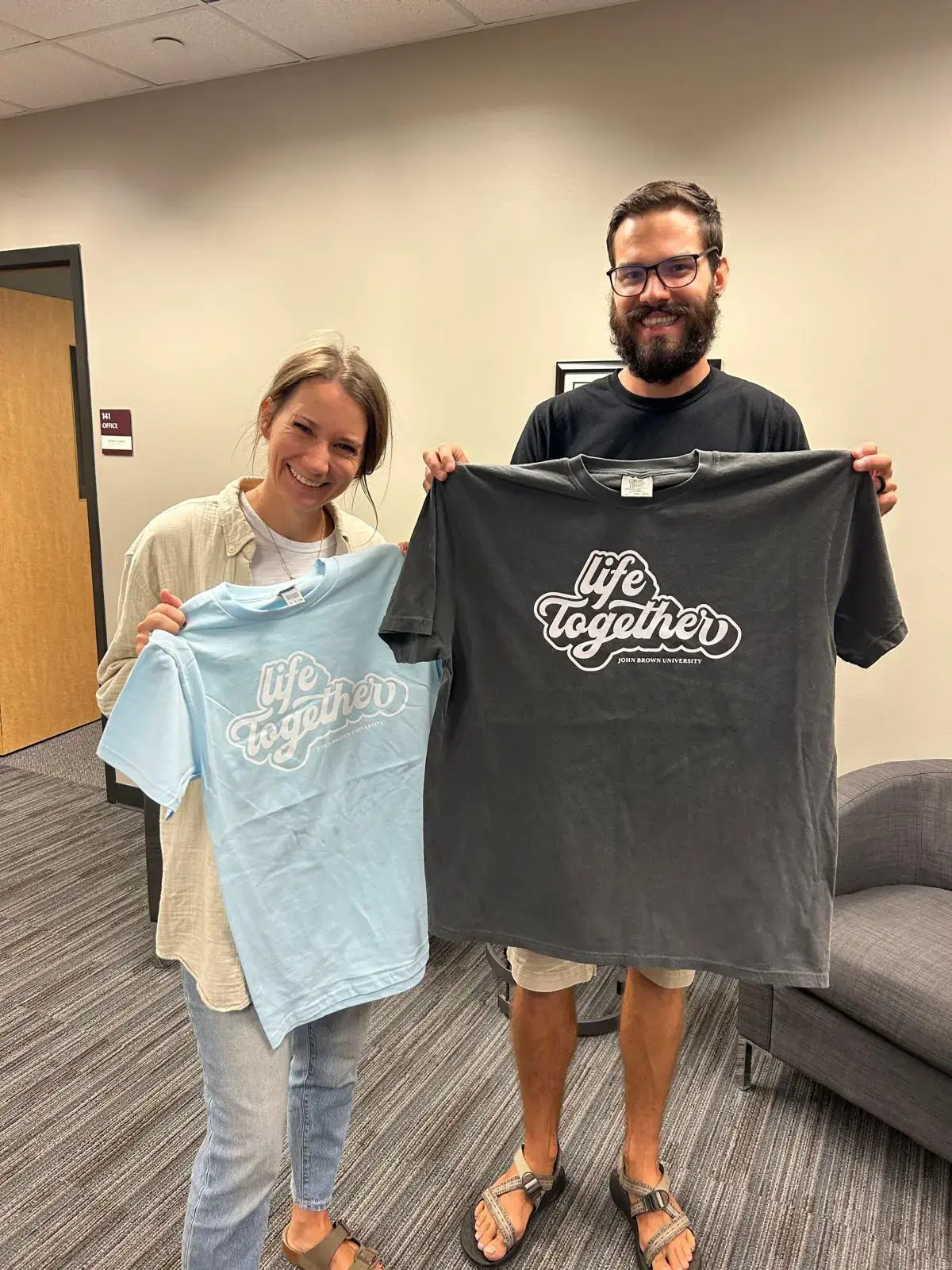 John from Splor with John Brown University staff, holding custom dorm tee shirts